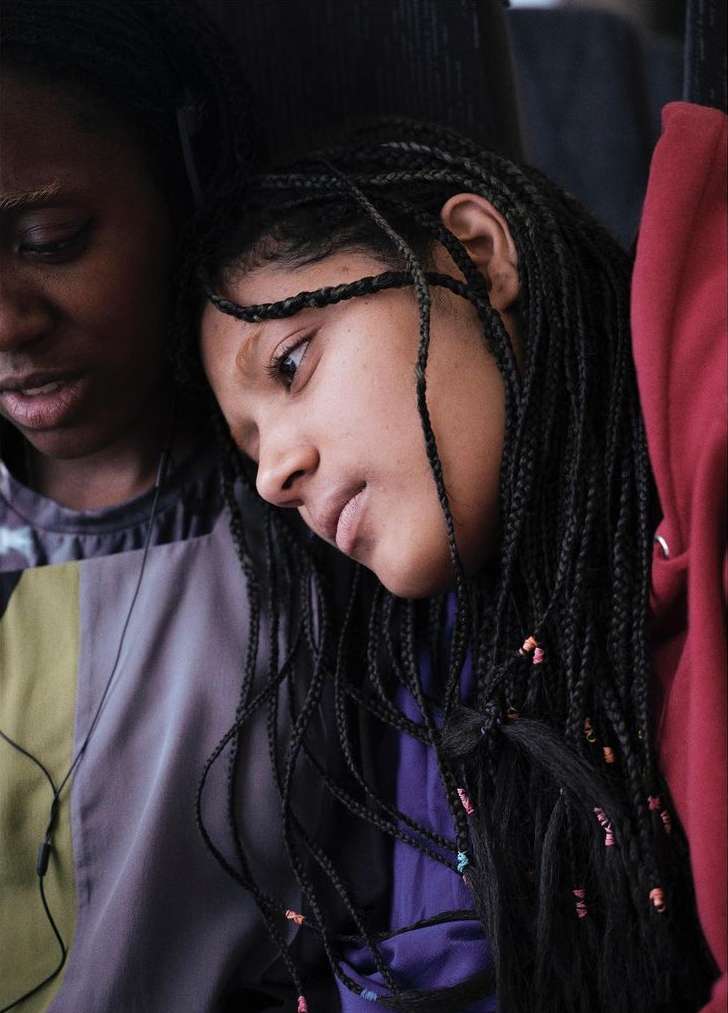 Close-up shot of two African American young women with braided hair, one looking off to the side in a contemplative mood.