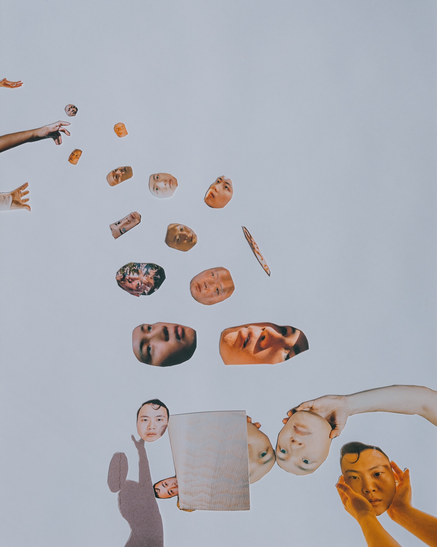 Collage featuring floating and layered human faces, heads, and arms against a bright white background in a conceptual composition.