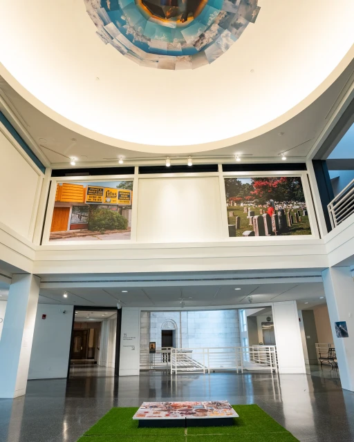 Interior view of an art gallery featuring large photographs and modern architecture with a circular ceiling installation.