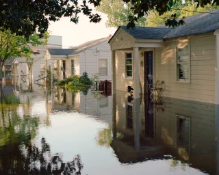 A row of single-story suburban houses partially submerged in floodwater, captured by photographer Tommy Kha in New York.