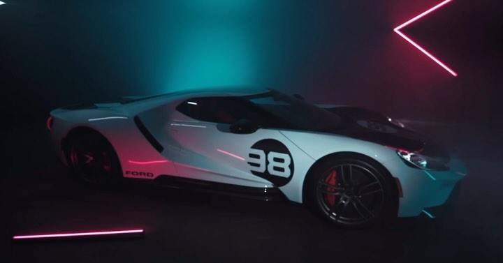 White Ford GT race car with the number 38 in a photo studio setting with neon accent lighting. Automotive photography.