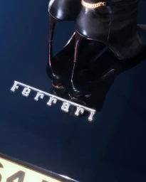 Close-up of black high heels with gold chain detail standing on the glossy dark surface of a Ferrari car with visible badging.
