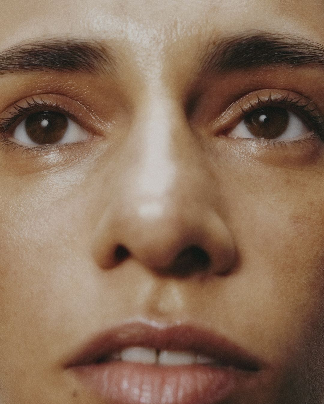 Close-up shot of an adult woman's face featuring her eyes, nose, and mouth. Soft, diffused lighting accentuates skin's natural texture and tones.