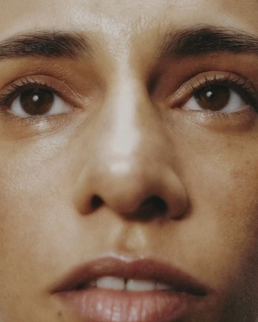 Close-up shot of an adult woman's face featuring her eyes, nose, and mouth. Soft, diffused lighting accentuates skin's natural texture and tones.