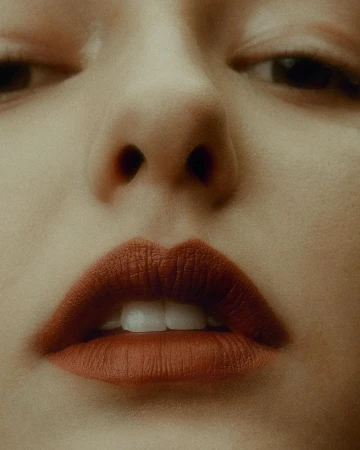 Close-up portrait of a woman face featuring red lipstick and visible skin texture photographed by Troy Covey in New York