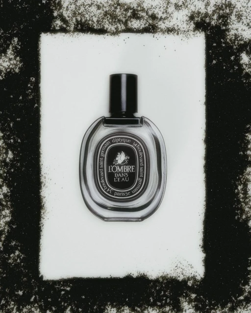 Studio shot of a Diptyque L'Ombre Dans L'Eau perfume bottle against a white backdrop with a black granular border.