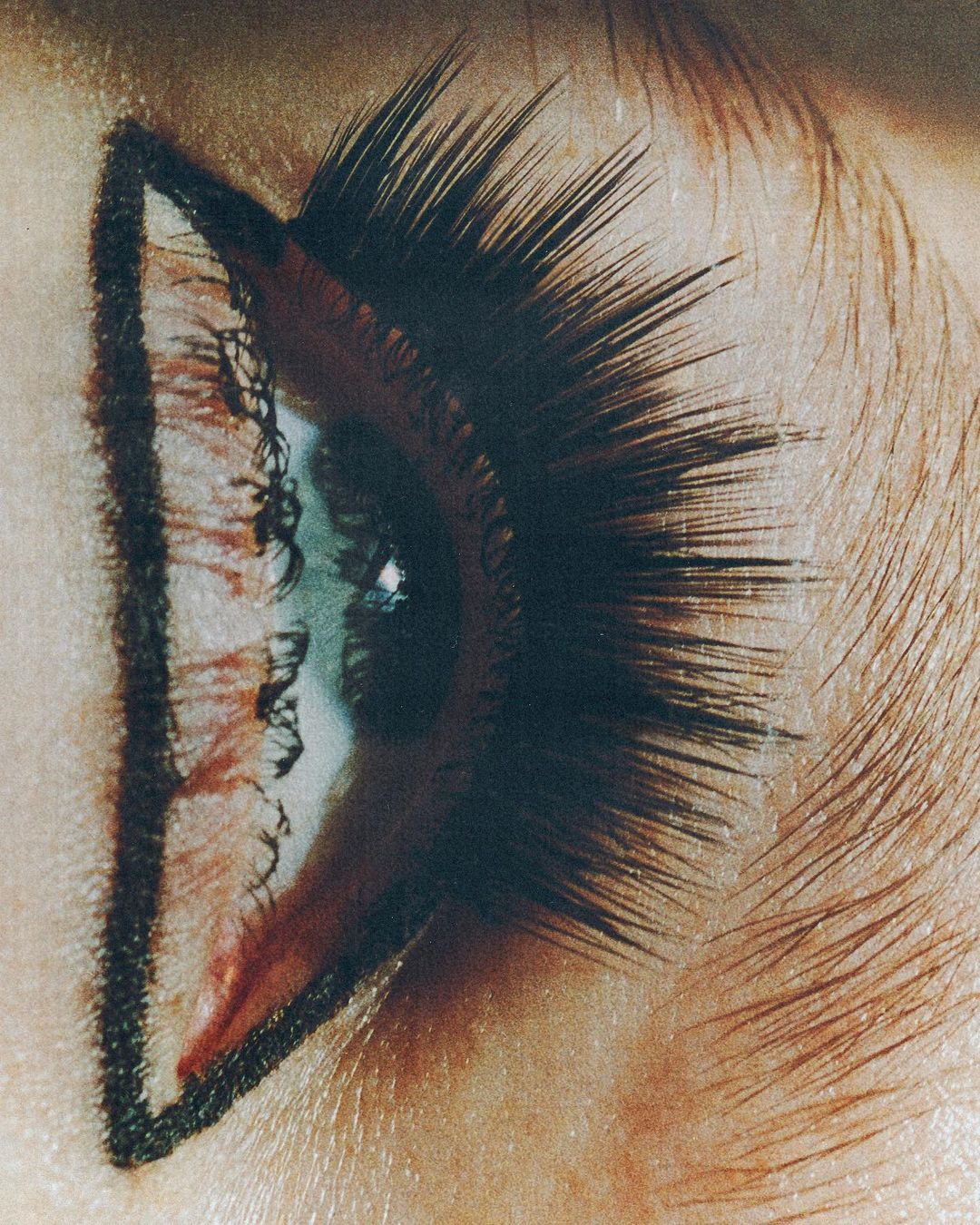 Close-up of an eye with dramatic makeup featuring graphic black eyeliner and striking false eyelashes for a beauty or fashion concept.