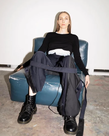 Woman wearing black long sleeve top and wide leg trousers seated on blue armchair by photographer Tuhin Chandra.
