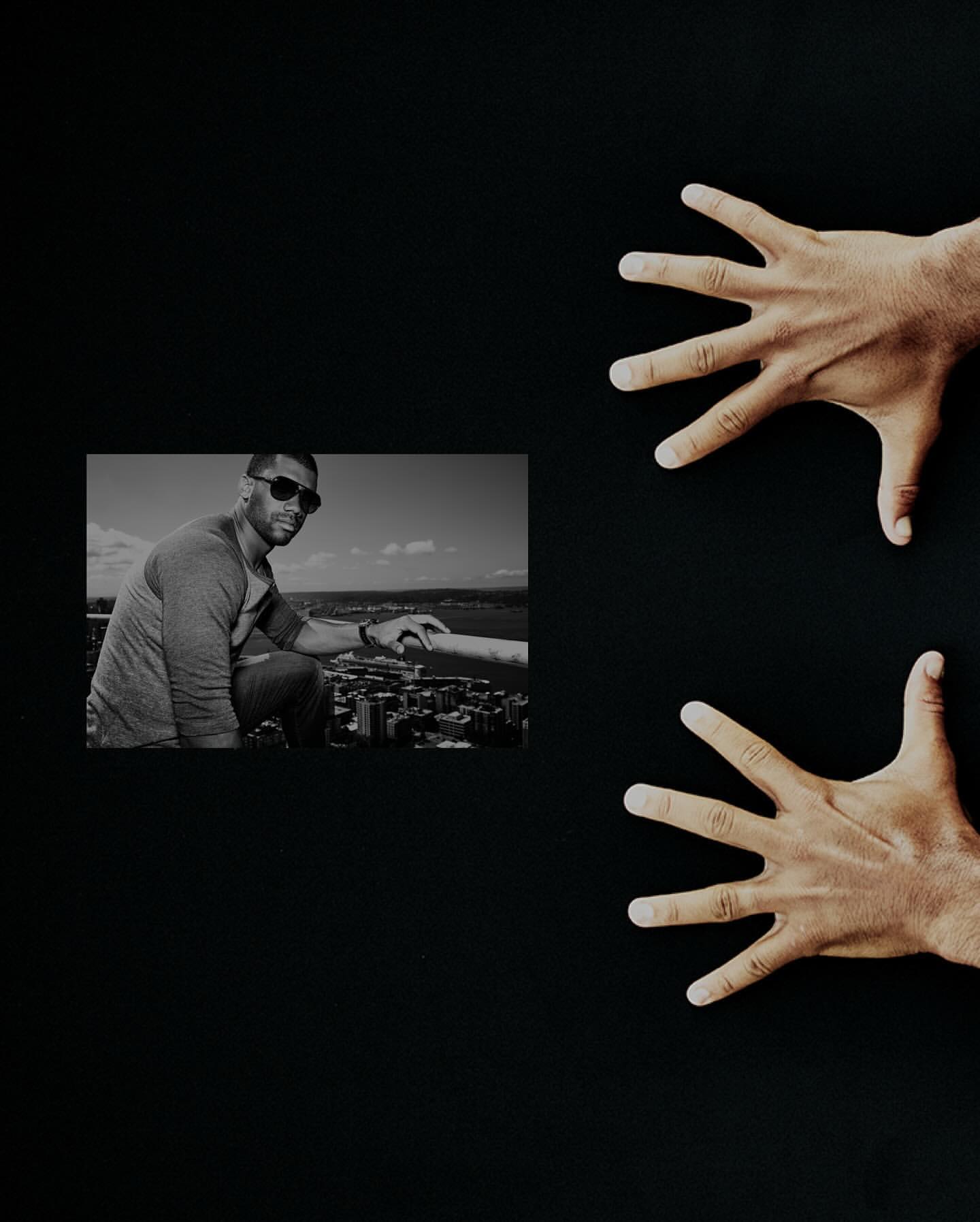 A black and white photo features two hands on the right side of the frame and a black and white photo of a man on the left.