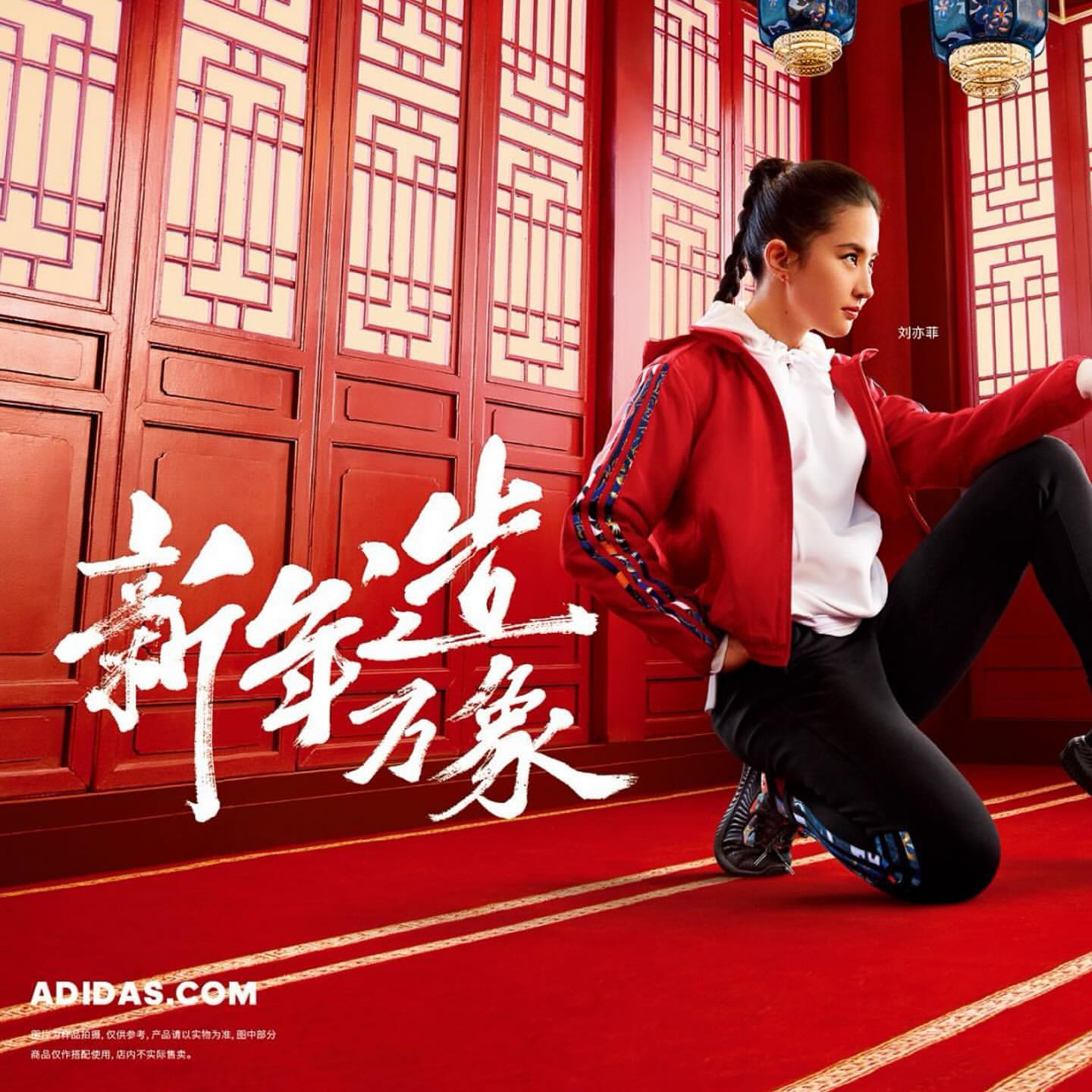 Asian woman in red jacket and black pants poses in front of an ornate red wall with traditional Chinese lanterns for Adidas ad.