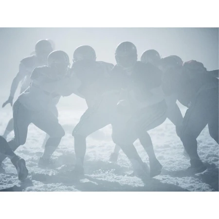 American football players in uniform during game with helmets on, in a foggy outdoor setting, showcasing action and team sport. 