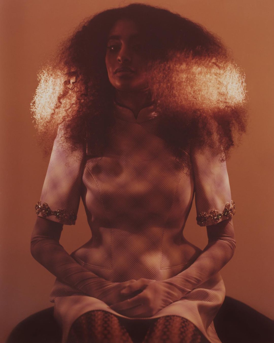 Portrait of a woman with voluminous dark hair wearing a patterned dress, captured in warm sepia tones by Turkina Faso.