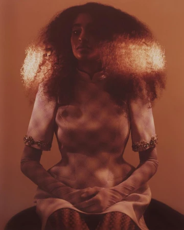 Portrait of a woman with voluminous dark hair wearing a patterned dress, captured in warm sepia tones by Turkina Faso.