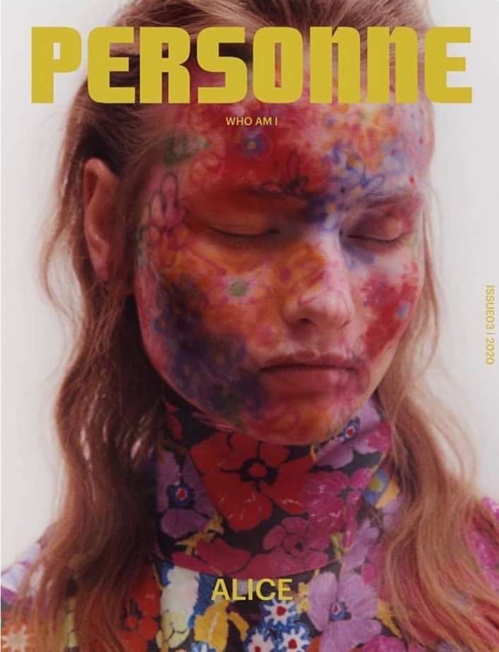 Magazine cover featuring a model with colorful floral face paint and a matching floral high-neck top, against a neutral background.
