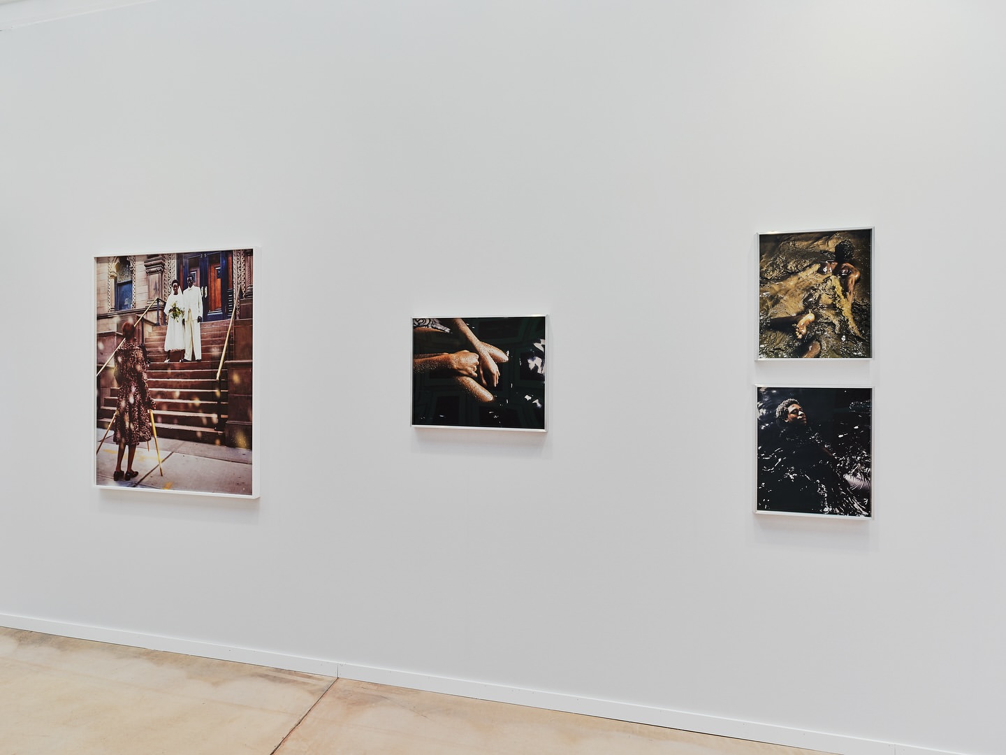 Art gallery wall featuring framed photographs of diverse subjects, including figures on stairs and abstract water scenes in a bright, neutral space.
