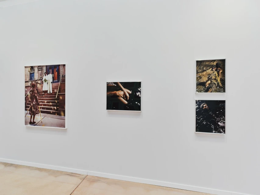 Art gallery wall featuring framed photographs of diverse subjects, including figures on stairs and abstract water scenes in a bright, neutral space.