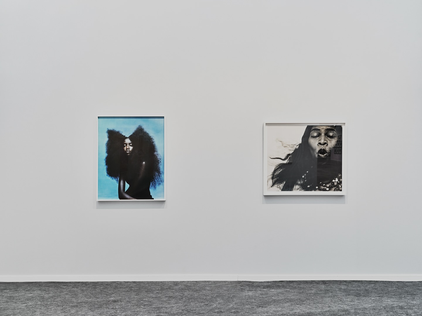 Two framed portraits of women on a white gallery wall. One woman with dark hair gazes forward. The other blows air. Minimalist and modern.