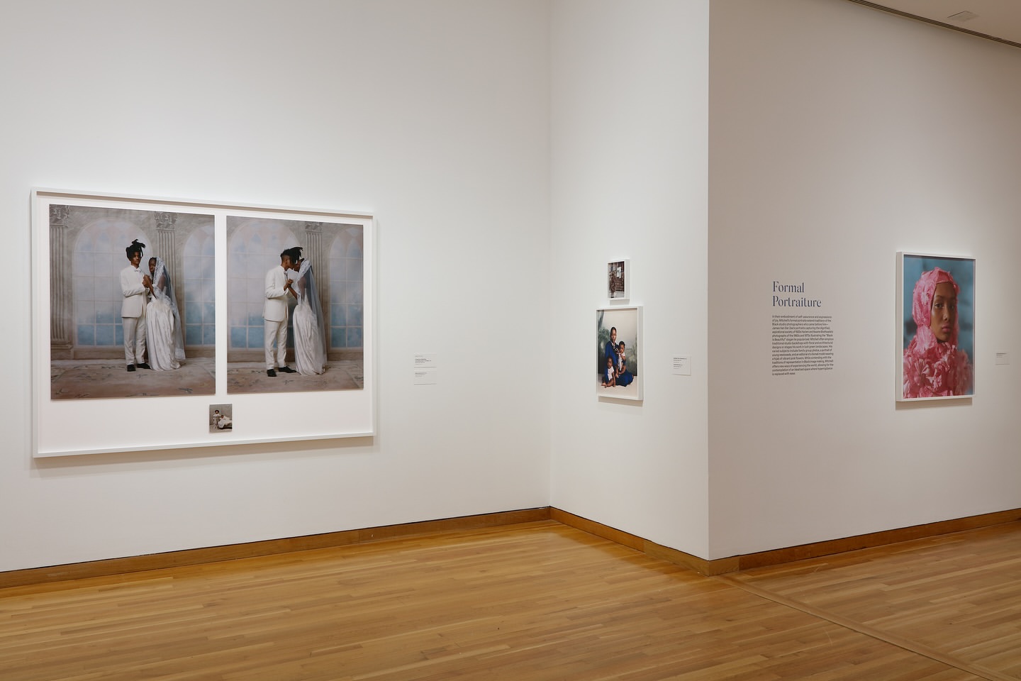 Two framed wedding photos of a bride and groom on display in an art gallery with multiple other images and a light wood floor.