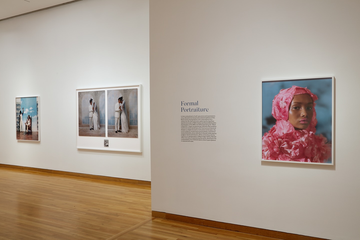 Interior museum view of three framed portraits on a white wall with a light brown wood floor in the foreground of the scene.