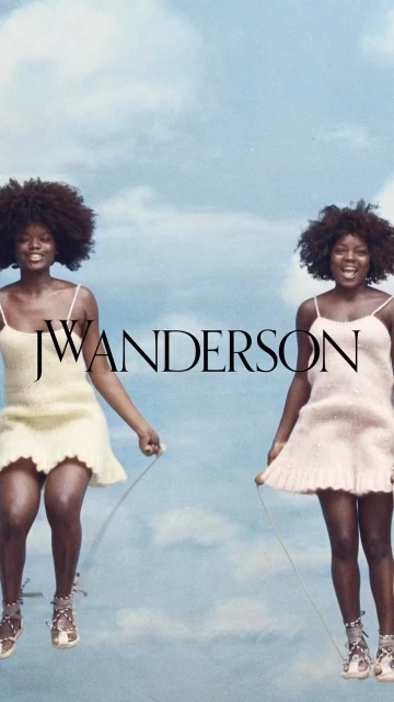 Two African-descent women jump rope in pastel dresses and gladiator sandals against a bright sky with wispy clouds, fashion editorial.