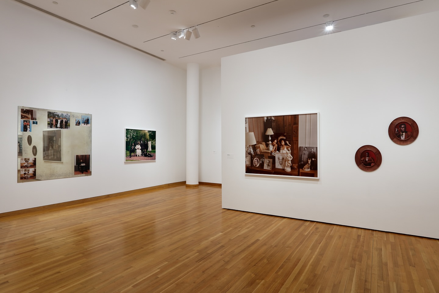 Art gallery features three framed photographs on a white wall, enhanced by spotlights and a polished wooden floor, creating a serene viewing space.