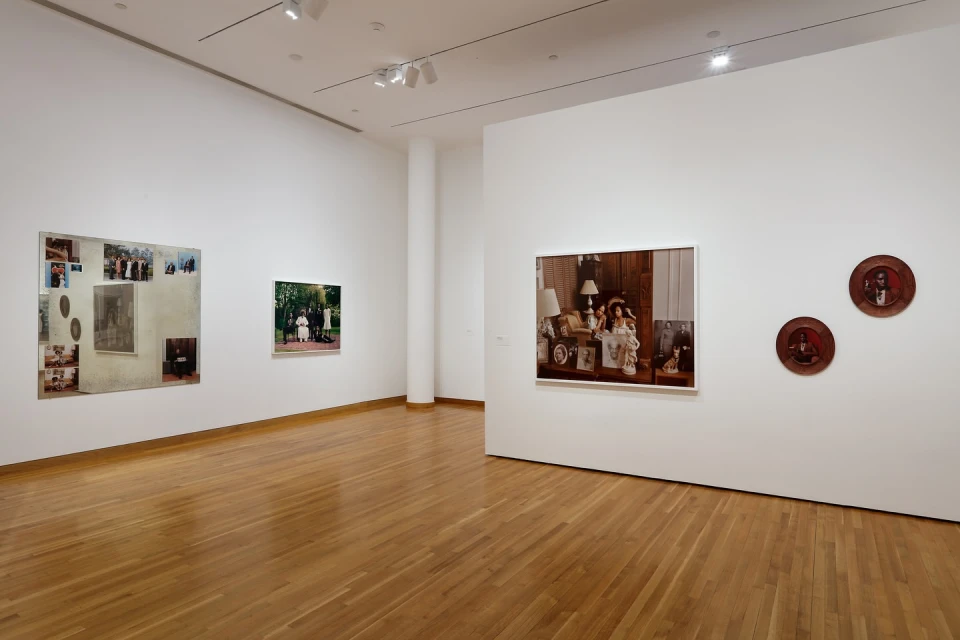 Art gallery features three framed photographs on a white wall, enhanced by spotlights and a polished wooden floor, creating a serene viewing space.