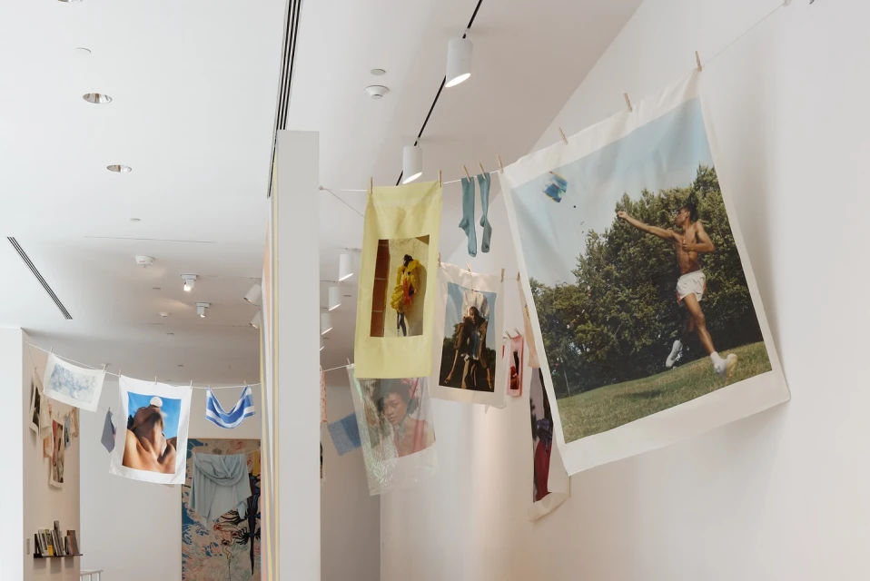 Art gallery view of photographs and fabric prints hung on a line with clothespins, creating a unique and artistic display.