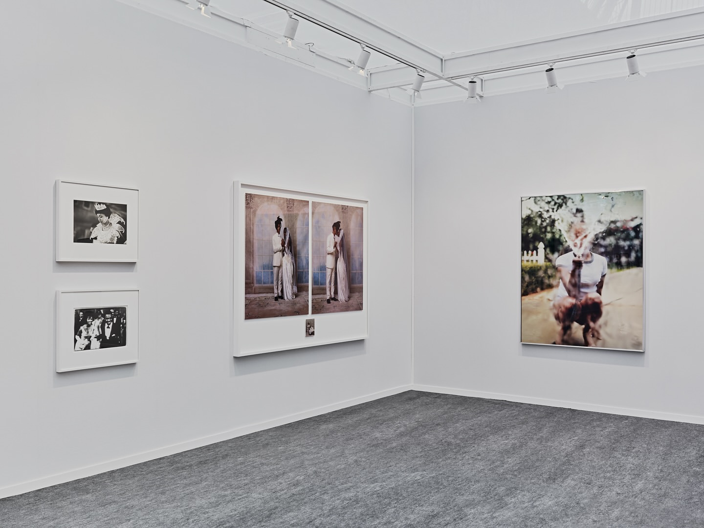 Art gallery exhibition featuring framed portrait and figure photography on white walls under track lighting, complemented by a gray carpet.