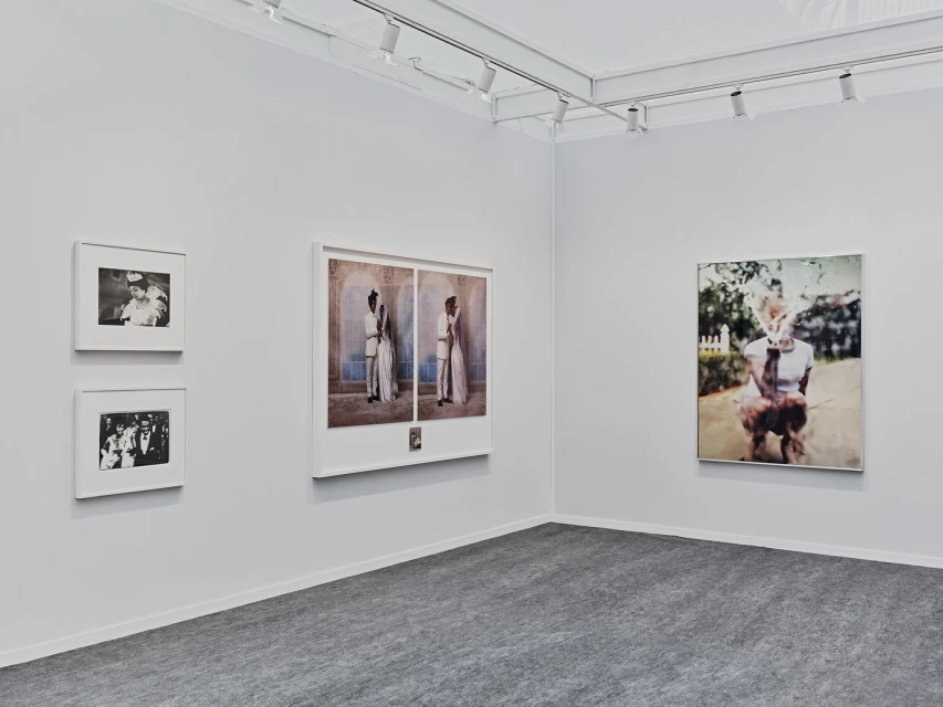 Art gallery exhibition featuring framed portrait and figure photography on white walls under track lighting, complemented by a gray carpet.