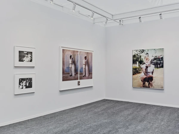 Art gallery exhibition featuring framed portrait and figure photography on white walls under track lighting, complemented by a gray carpet.