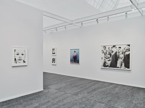 Interior view of an art gallery with multiple framed photographs hanging on the walls and gray flooring, illuminated by track lighting.