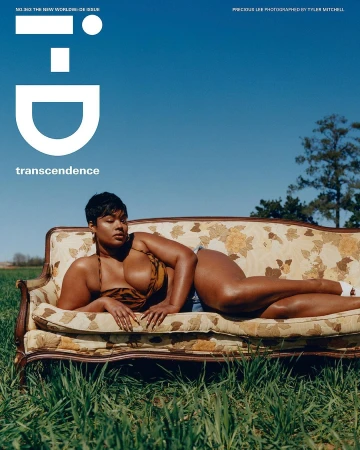 Model lying on a vintage floral couch outdoors in a grassy field under a clear blue sky