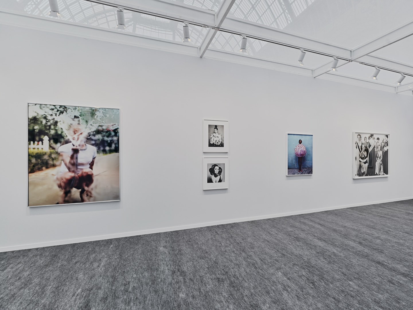 Art gallery exhibition featuring framed photographic portrait art, showcasing a variety of subjects and styles on a light wall.