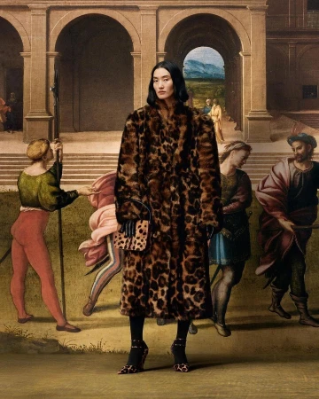 A woman poses in a leopard-print coat against a Renaissance-style mural, blending modern fashion with classic art aesthetics.