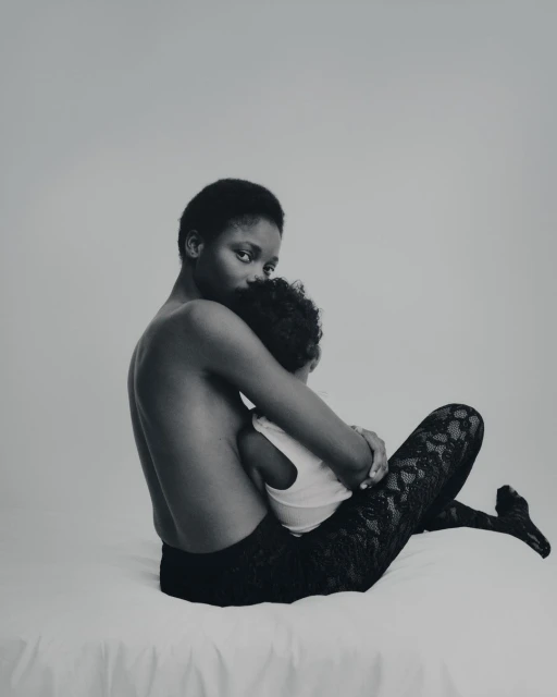 A mother gently embraces her child in a monochrome studio portrait, showcasing a tender moment of connection and familial love.