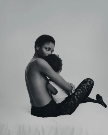 A mother gently embraces her child in a monochrome studio portrait, showcasing a tender moment of connection and familial love.