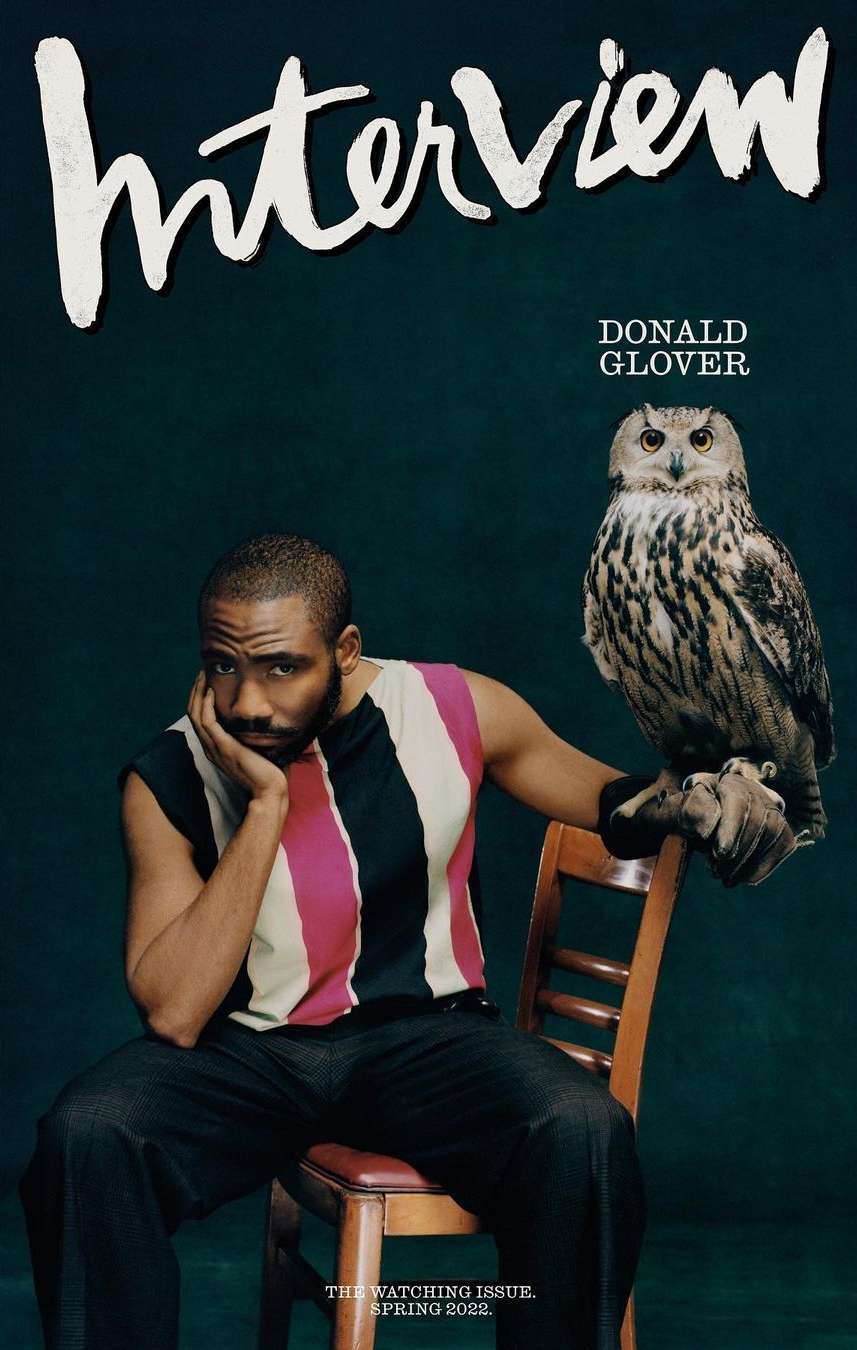 Interview magazine cover featuring Donald Glover seated with a Eurasian eagle-owl, set against a dark green backdrop in a portrait-style.