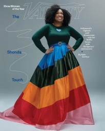 Shonda Rhimes standing on a grey backdrop wearing a green top and a colourful striped ball gown photographed by Tyler Twins.