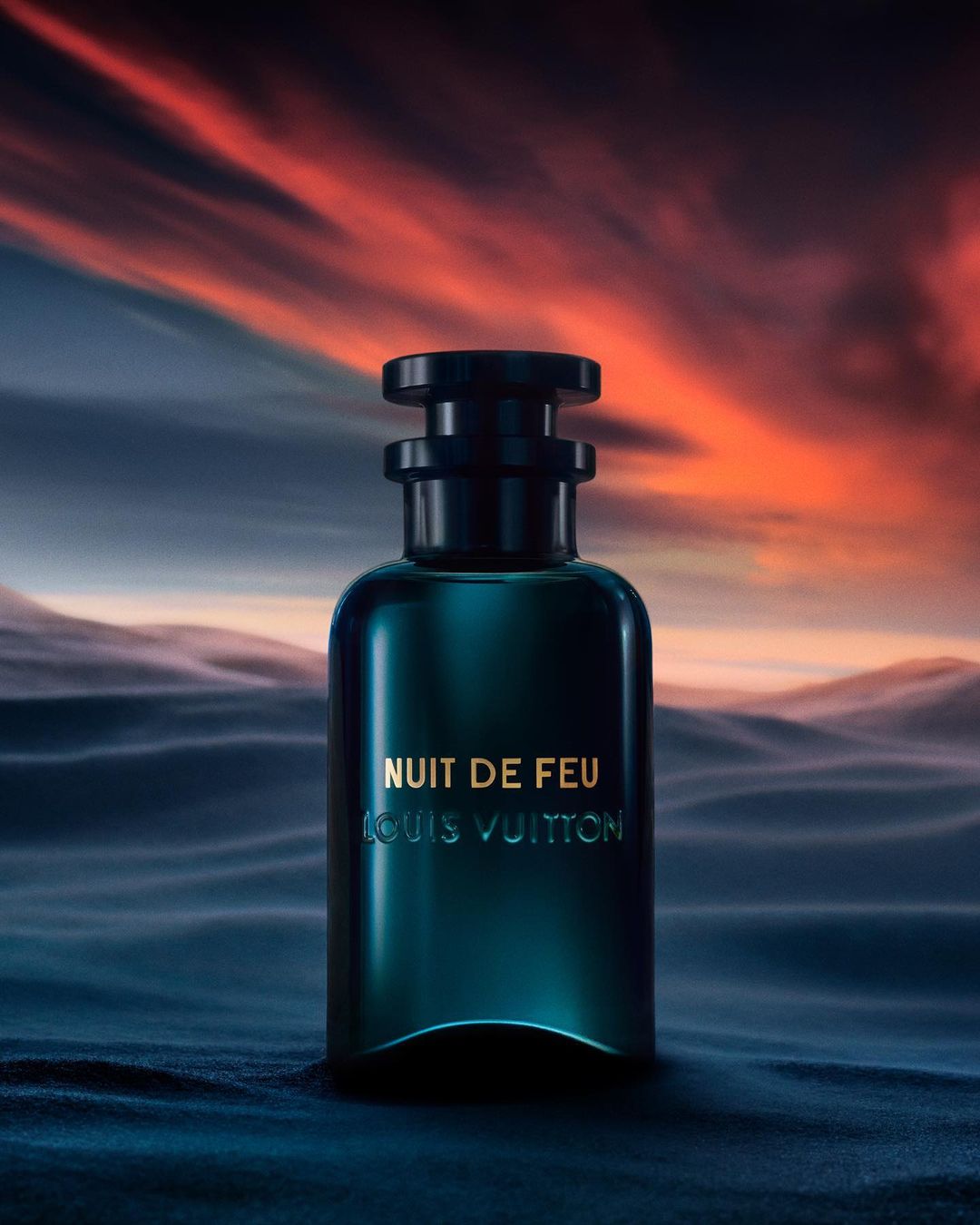 A sleek, dark perfume bottle by Louis Vuitton is centered against a gradient sky, creating a luxurious and atmospheric product shot.