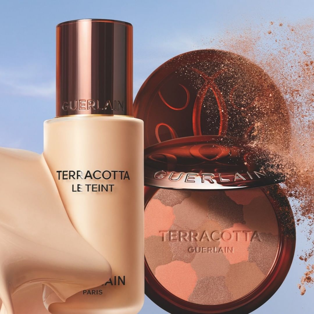 Guerlain Terracotta foundation and bronzer compact for beauty and cosmetics product shot against a soft blue background with powder.