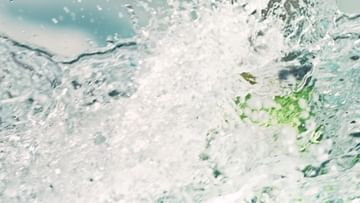 Close-up of splashing water with a green lime in the background, creating a dynamic and refreshing visual.