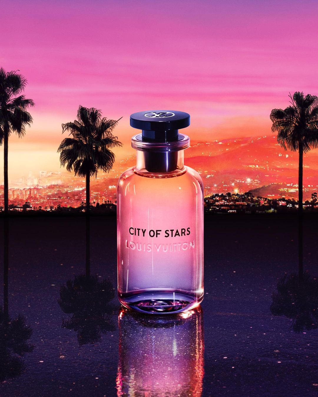 Louis Vuitton 'City of Stars' perfume bottle on a reflective surface, featuring palm trees, city lights, and a vibrant sunset backdrop.