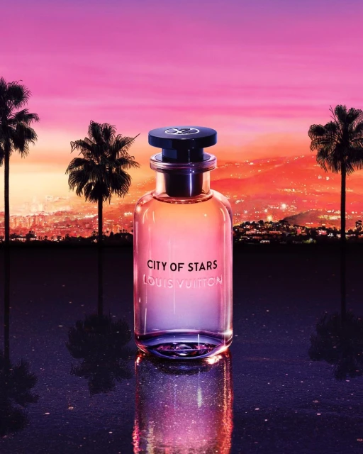 Louis Vuitton 'City of Stars' perfume bottle on a reflective surface, featuring palm trees, city lights, and a vibrant sunset backdrop.
