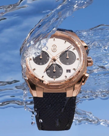 Luxury gold wristwatch with a black band displayed with a water splash, showcasing details against a clear blue background.