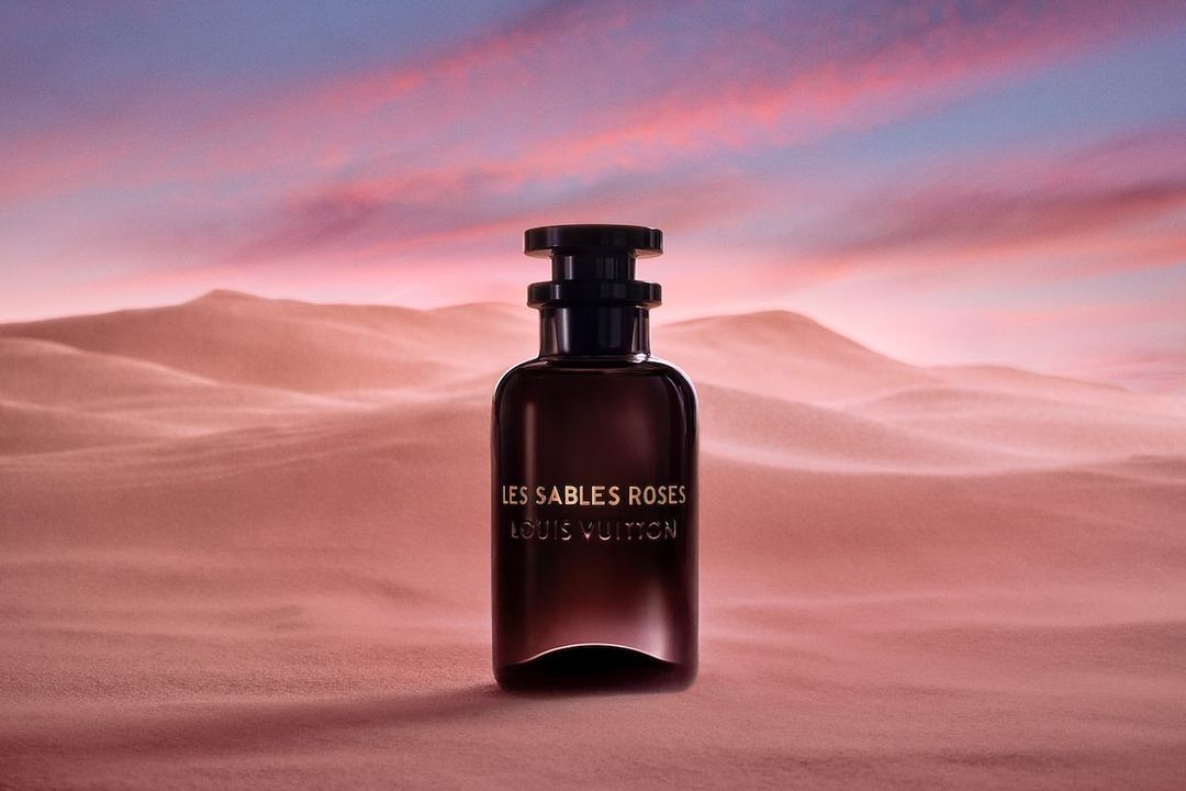 Product shot of Louis Vuitton perfume bottle in desert landscape, featuring gradient sunset sky with blue, purple, and pink hues.
