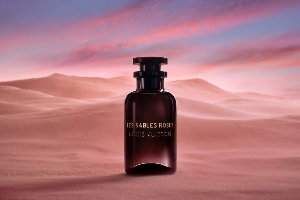 Product shot of Louis Vuitton perfume bottle in desert landscape, featuring gradient sunset sky with blue, purple, and pink hues.