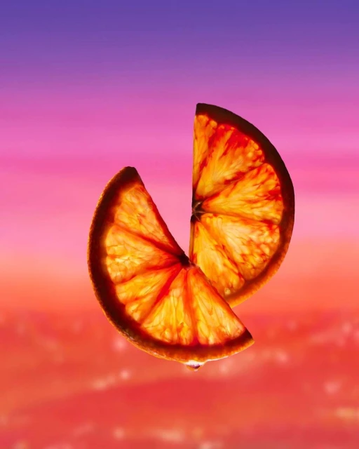 Two orange segments, stacked, and backlit against a blurred pink and orange background, highlighting vibrant colors and citrus texture.