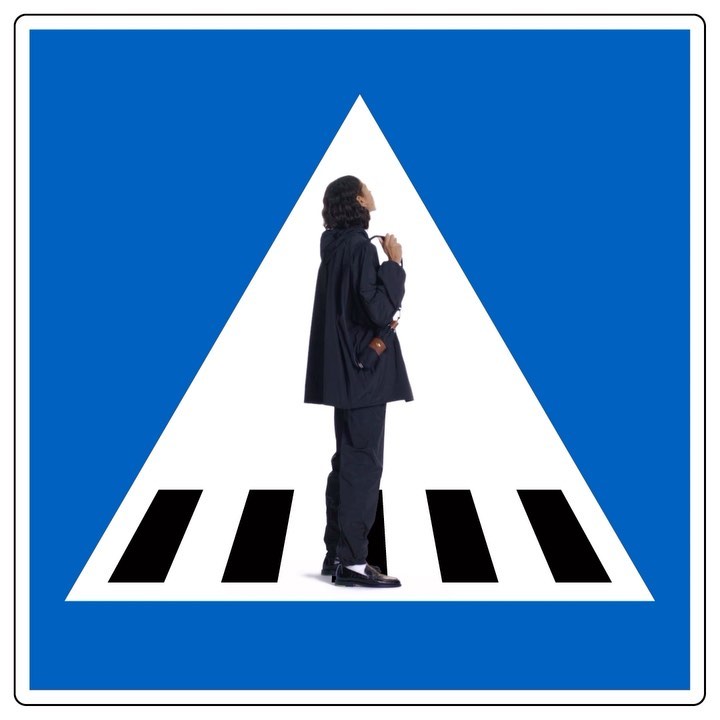 Person in dark suit on pedestrian crossing sign. Conceptual shot of modern fashion with blue and white graphic design.