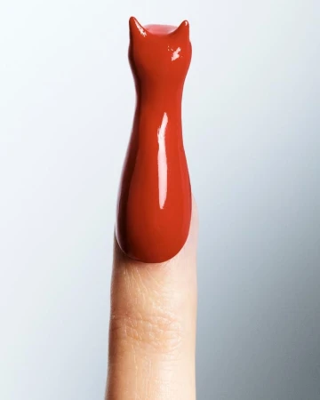 Close-up studio shot of a single adult finger coated in red nail polish, styled into the shape of a cat figure with pointed ears.
