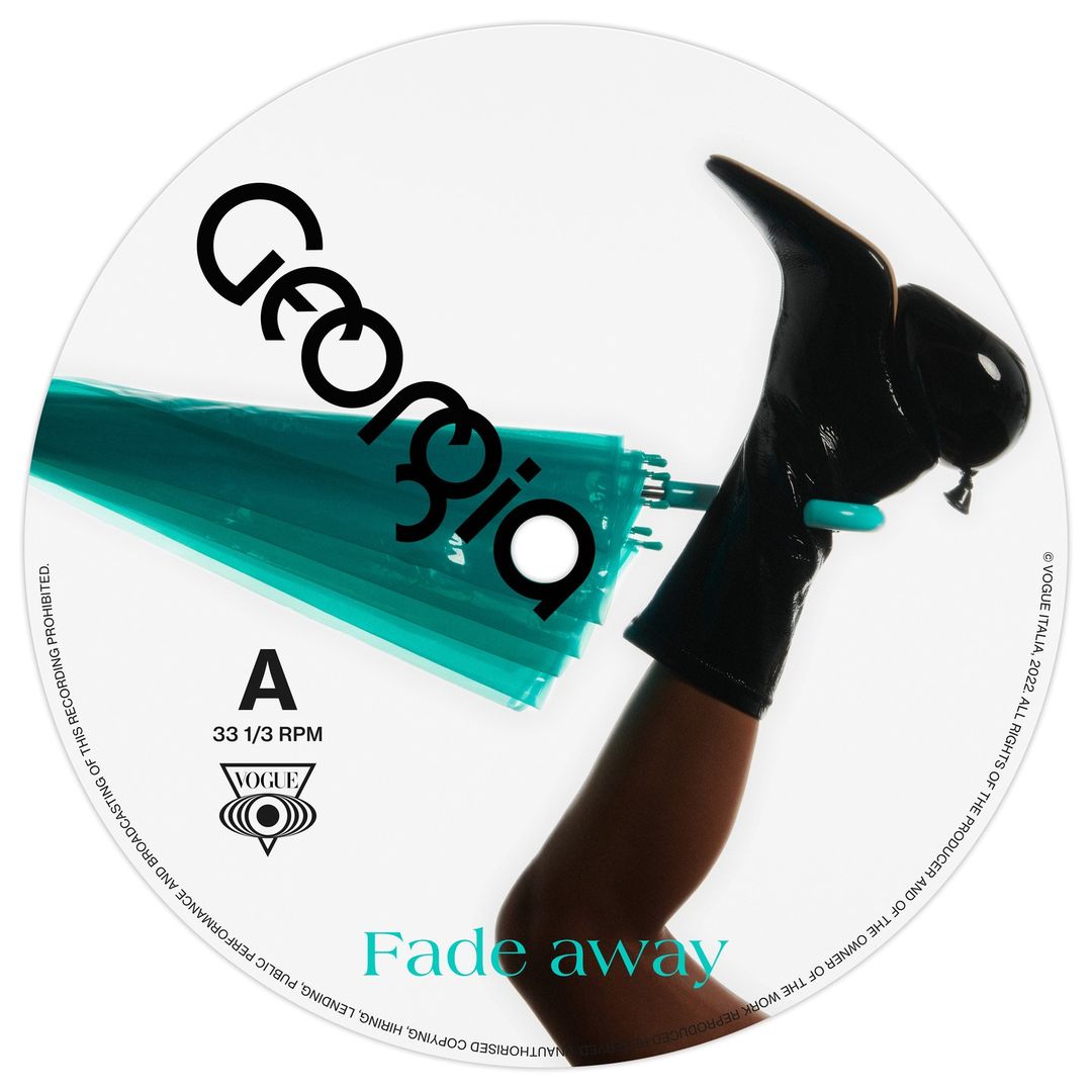 Close-up vinyl record cover featuring a woman's leg with black high-heeled shoe, turquoise umbrella, set against a white backdrop.